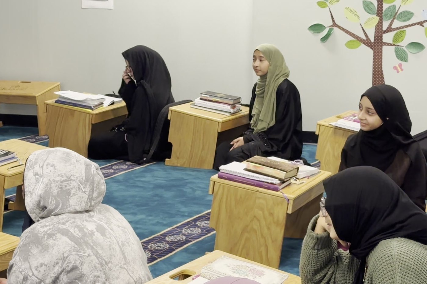 Oceans Academy students studying Qur'an at low desks in the prayer hall